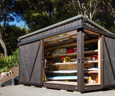 a wooden shed with surfboards in it's door and shelves on the side