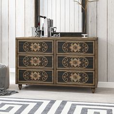 a dresser with an ornate design on the drawers and mirror above it, in front of a white wooden wall