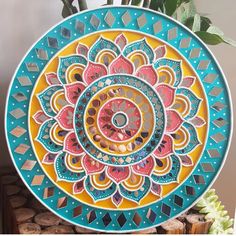 a colorful plate sitting on top of a table next to a vase filled with flowers