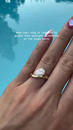 a woman's hand with a ring on her finger next to a swimming pool