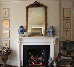 a living room with a fire place, mirror and vases on the mantel