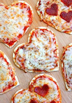 heart shaped pizzas with cheese and pepperoni arranged in the shape of hearts on a cutting board