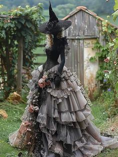 a woman wearing a dress made out of old clothes and flowers is standing in the grass