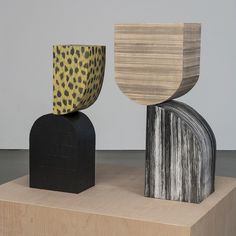 three different shapes and sizes of wood on top of a wooden block in front of a white wall