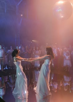 two women in white dresses dancing on stage