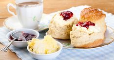 scones with jam and butter are on a plate next to a cup of coffee