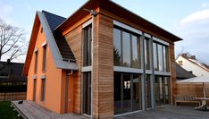 an orange house with large windows and wooden deck