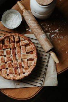 a pie sitting on top of a cooling rack next to a bowl and spatula