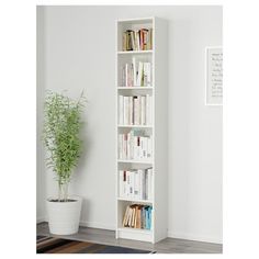 a tall white book shelf with books on it and a potted plant in the corner