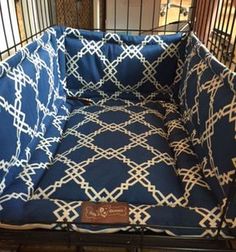 a blue and white dog bed that is in a metal cage with a name tag on it