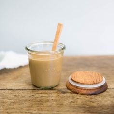 a glass jar filled with peanut butter next to a wooden spoon on top of a table