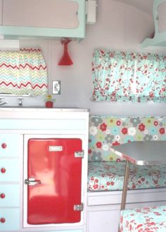 the interior of a small camper with bunk beds and red refrigerator freezer in it