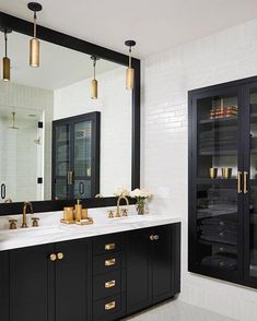 a black and white bathroom with gold accents on the sink, mirror and cabinets in front of it