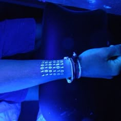 a person with a wrist watch on their arm in front of a blue light at night