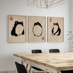 three framed pictures hang on the wall above a dining room table