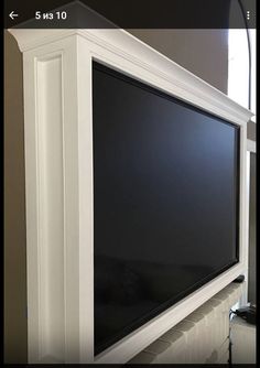 a flat screen tv mounted to the side of a wall in front of a window