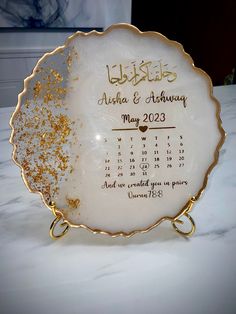 a white and gold plate sitting on top of a table with a calendar in the middle