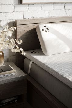 a bed with white sheets and pillows next to a wooden headboard on a nightstand