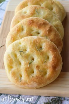 four biscuits on a cutting board with rosemary sprigs