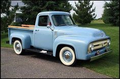 an old blue pick up truck parked in the grass