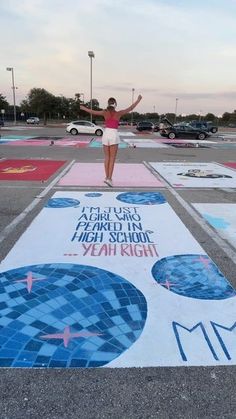 a woman standing on top of a painted parking lot with her arms in the air