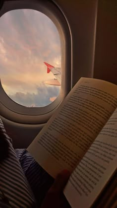 a person reading a book in front of an airplane window