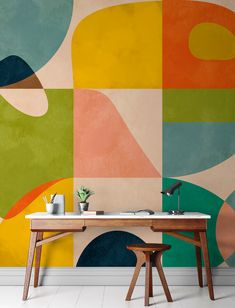 a desk and chair in front of a colorful wallpapered room with geometric shapes