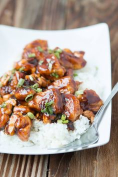 a white plate topped with rice covered in sauce and chicken pieces on top of it