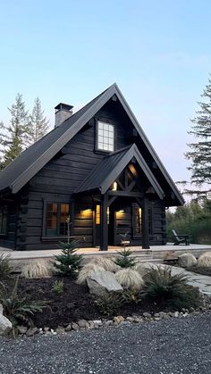 a log cabin with black shingles and stone walkway leading up to the front door