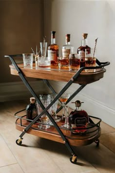 a bar cart with liquor bottles and glasses on it