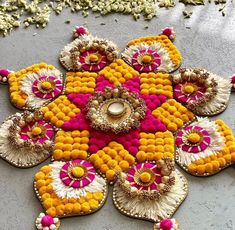 an intricately decorated flower design on the ground with beads and flowers around it's edges