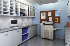 an office with blue walls and white cabinets