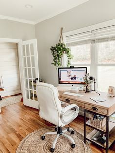 a home office with a desk, chair and computer monitor on the desk in front of a window