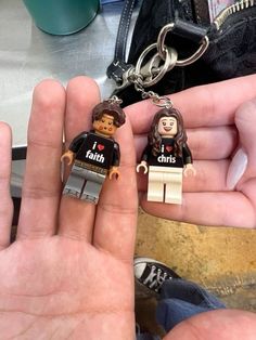 two legos are being held in the palm of someone's hand, one is wearing a keychain