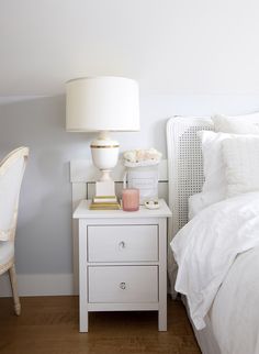 a bedroom with white bedding, nightstand and lamp