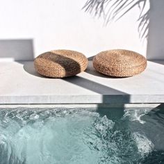 two wicker cushions sit on the edge of a swimming pool