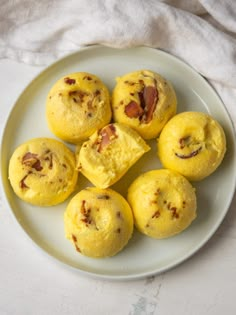 a white plate topped with yellow muffins covered in bacon