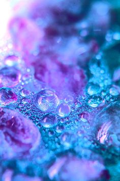 water droplets are seen on the surface of a blue and pink liquid filled with bubbles