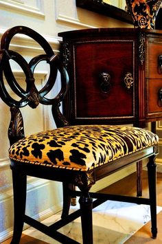 a chair with a leopard print upholstered seat sits in front of a dresser