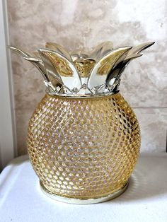 a gold glass vase with silver leaves on it