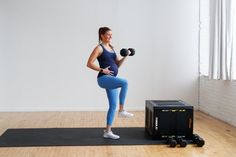 a woman is doing exercises with dumbbells on a mat in an empty room