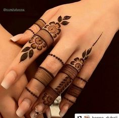 two hands with henna tattoos on them, one is holding the other's hand