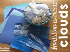 a bowl filled with white flowers sitting on top of a wooden table next to pictures