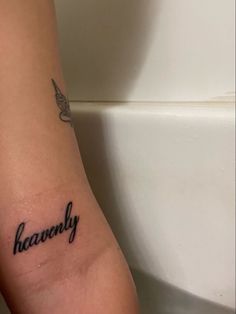 a woman's arm with the word heavenly tattooed on it