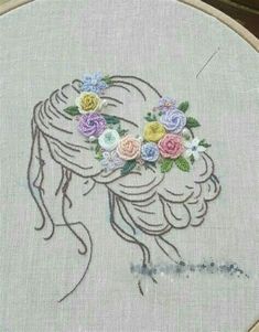 a woman's head with flowers in her hair is embroidered on a linen hoop