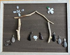 a frame with rocks and stones arranged in the shape of a house on top of a wooden table