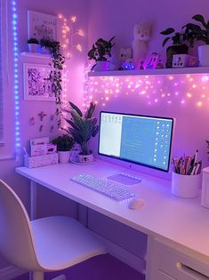 a white desk with a computer on it and some plants in front of the monitor