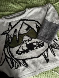 a sweater with an image of a car on it is laying on a green blanket