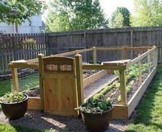 an outdoor vegetable garden with wooden fences and potted plants