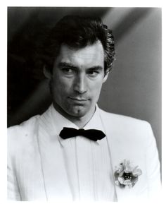 a black and white photo of a man in a tuxedo with a flower on his lapel